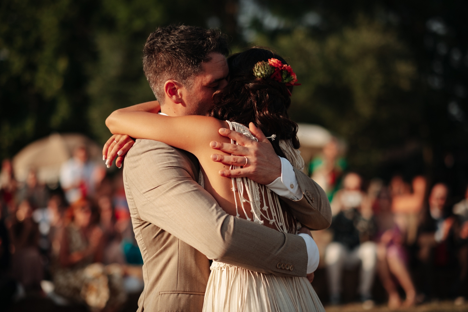 Groom hugging bride, who is in a macrame wedding dress by Atelier Zolotas