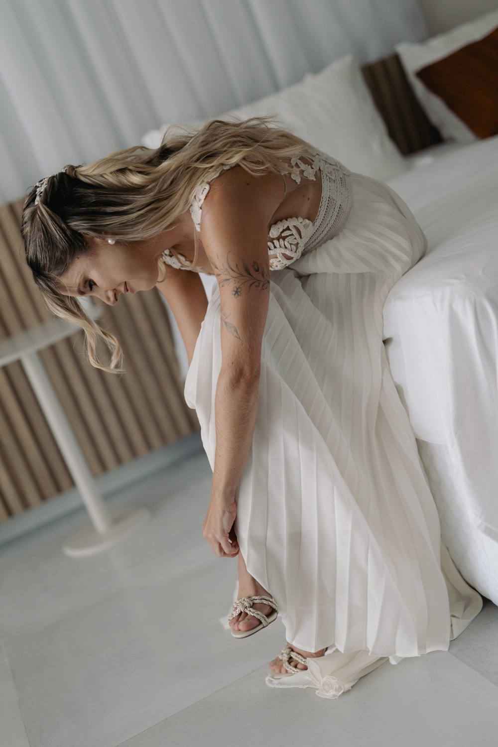 Bride wearing her shoes during wedding preparation, in a crochet wedding dress by Atelier Zolotas