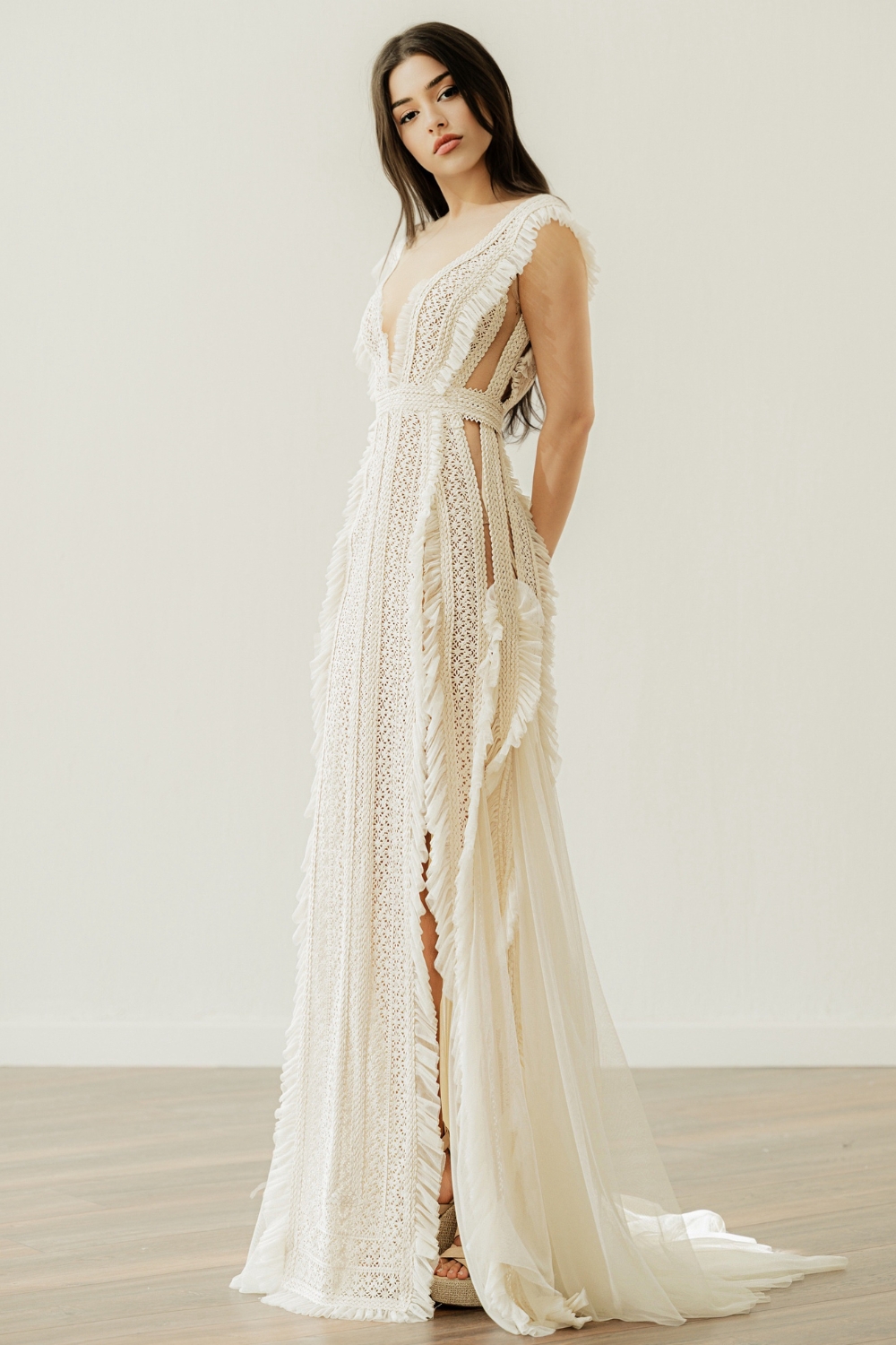 Bride wearing the Karly V-neck wedding dress by Atelier Zolotas with vintage lace, geometric trims, and removable semi-sheer sleeves in an open-back design