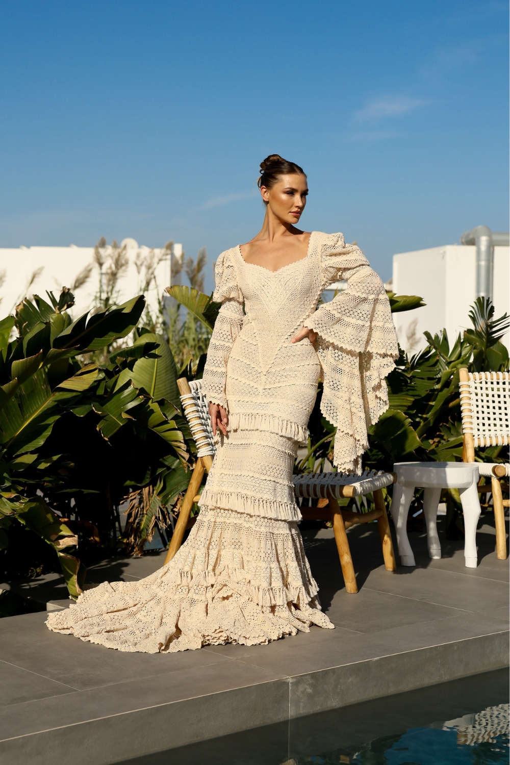 Bride posing in Santorini, in a long sleeve mermaid wedding dress with long bridal train